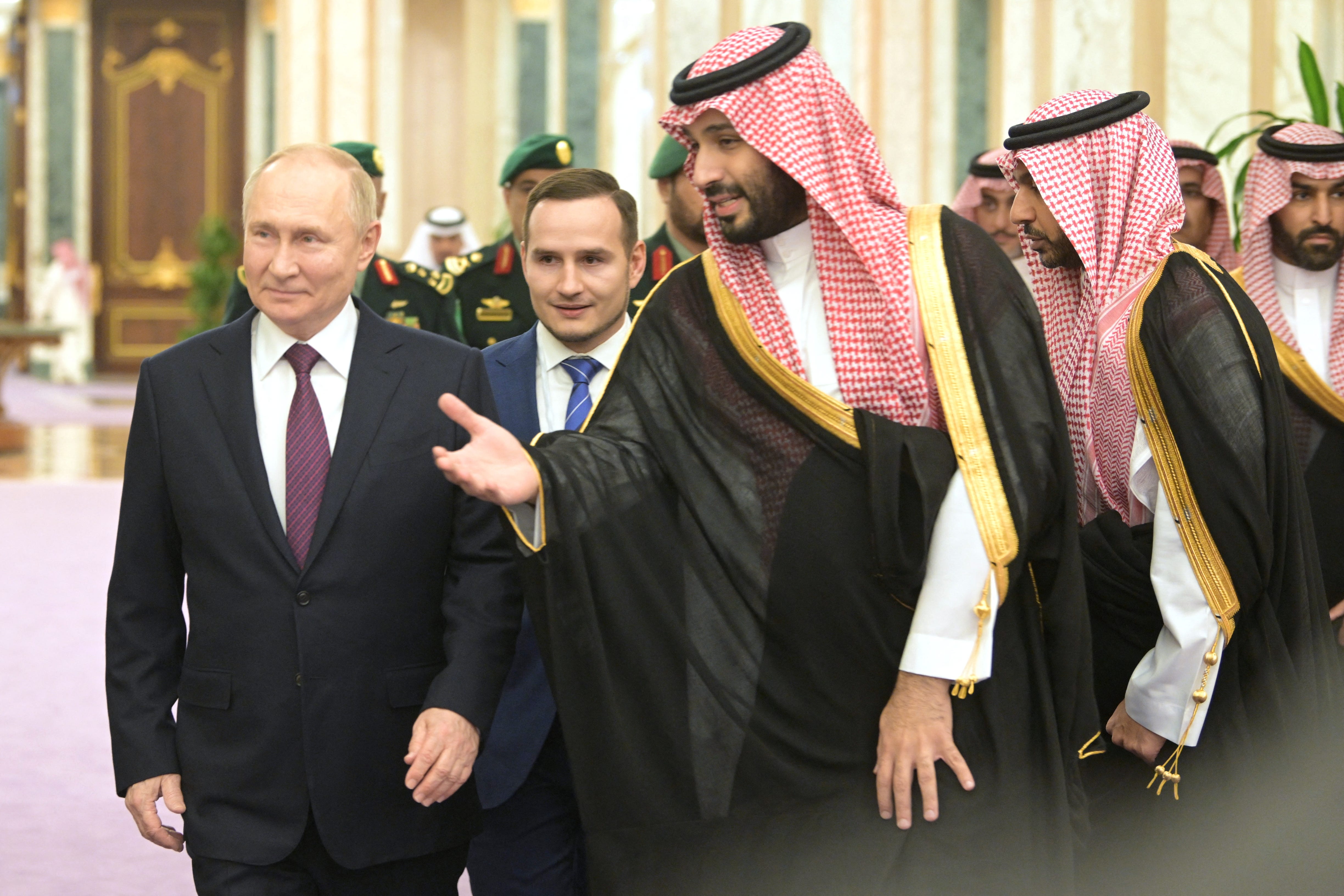 Russia's President Vladimir Putin and Saudi Crown Prince Mohammed bin Salman talking. Entourage in background.