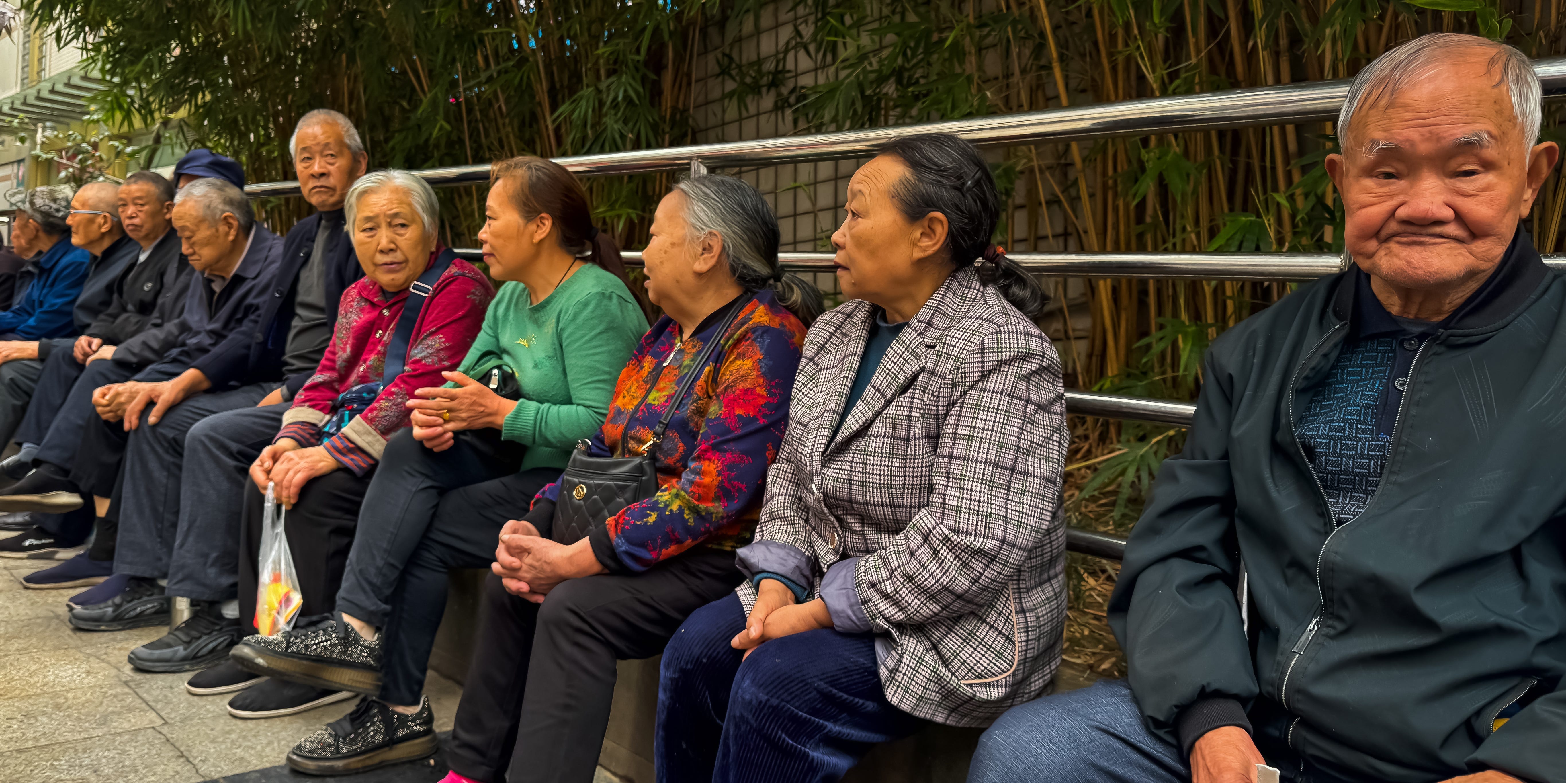 Line of older Chinese people on a sidewalk