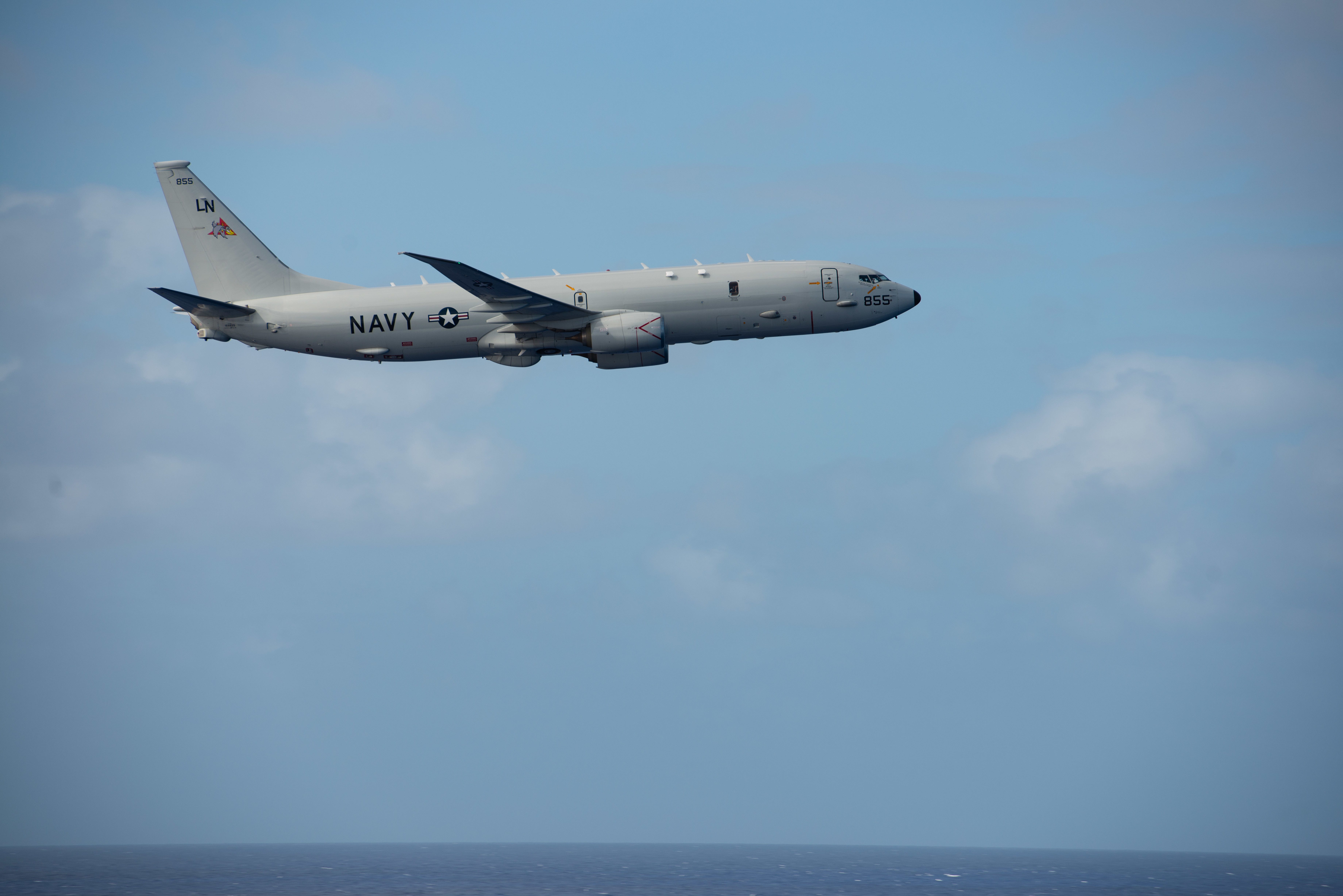 A US Navy P-8 flies by the aircraft carrier USS Nimitz.