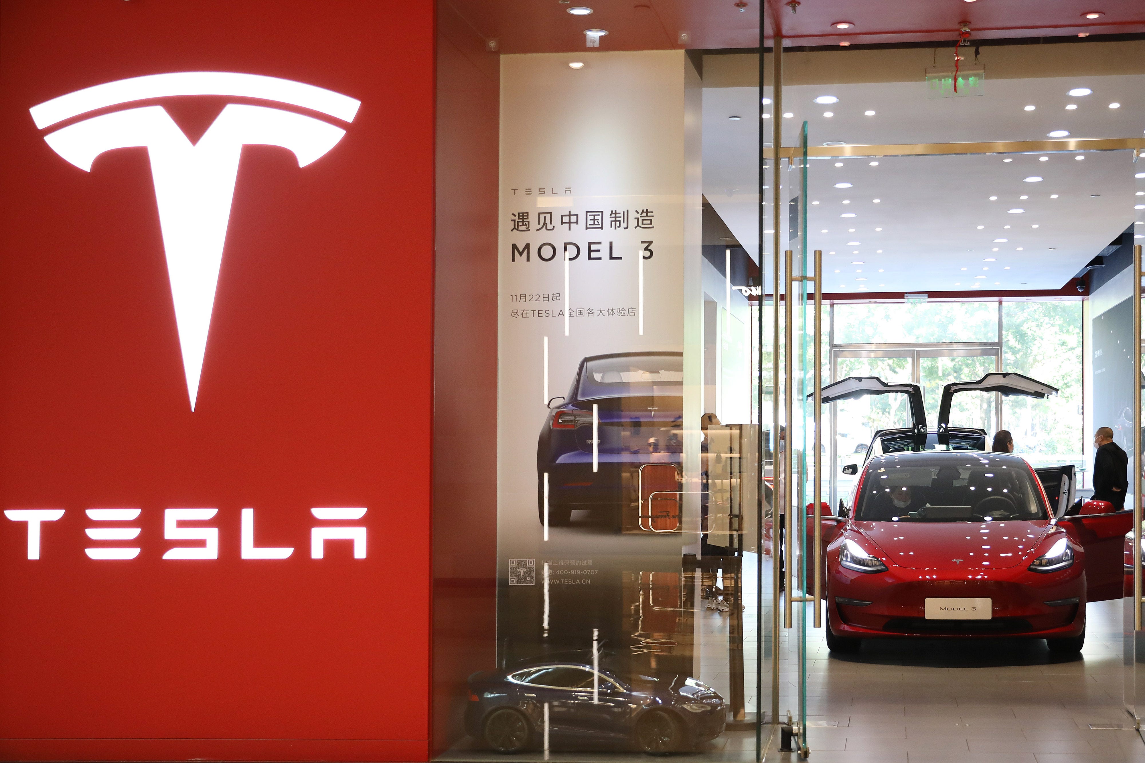 A composite image of the Tesla logo and Model 3 car in a showroom in China.