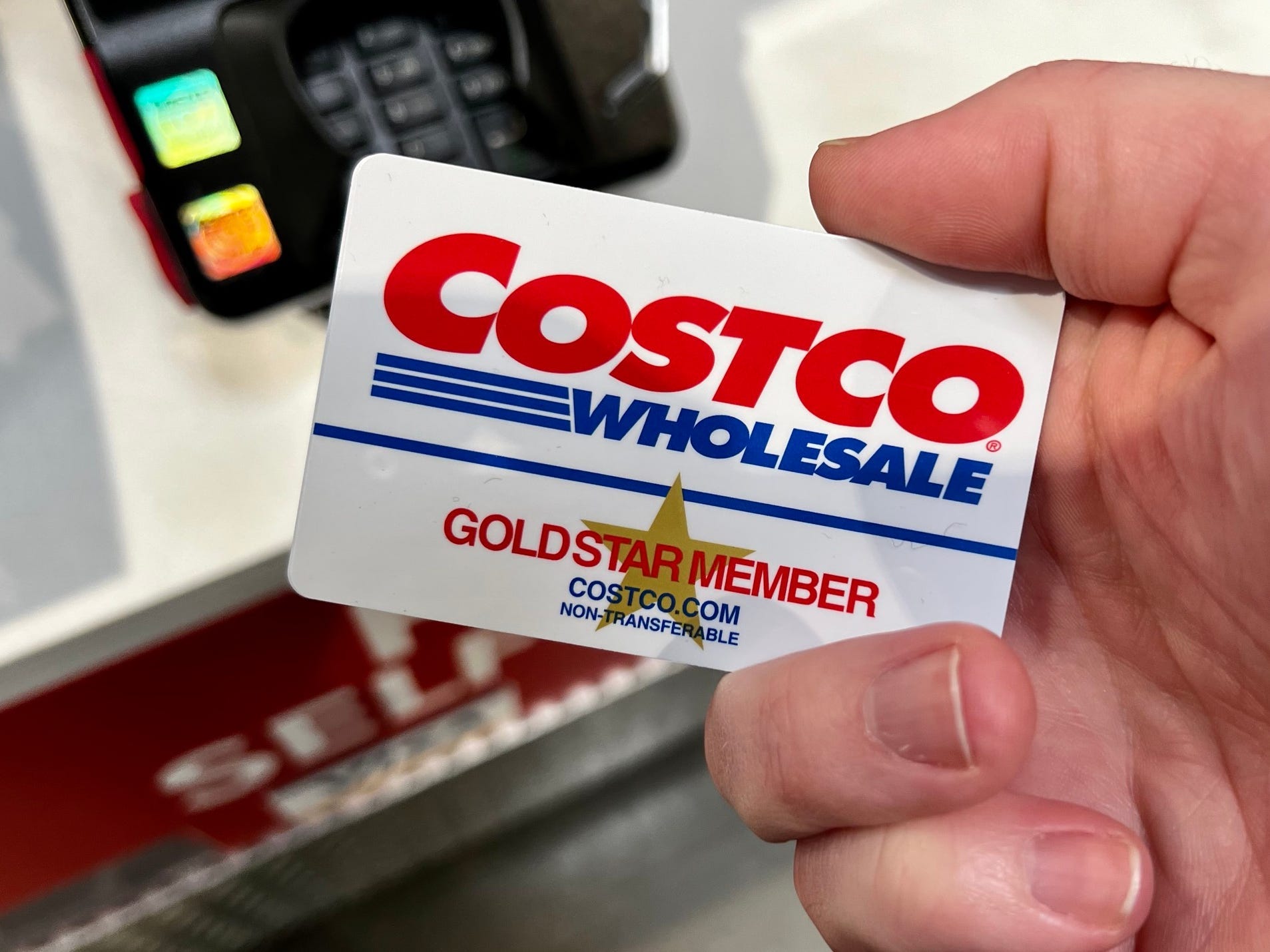 A hand holding a Costco gold-star membership card