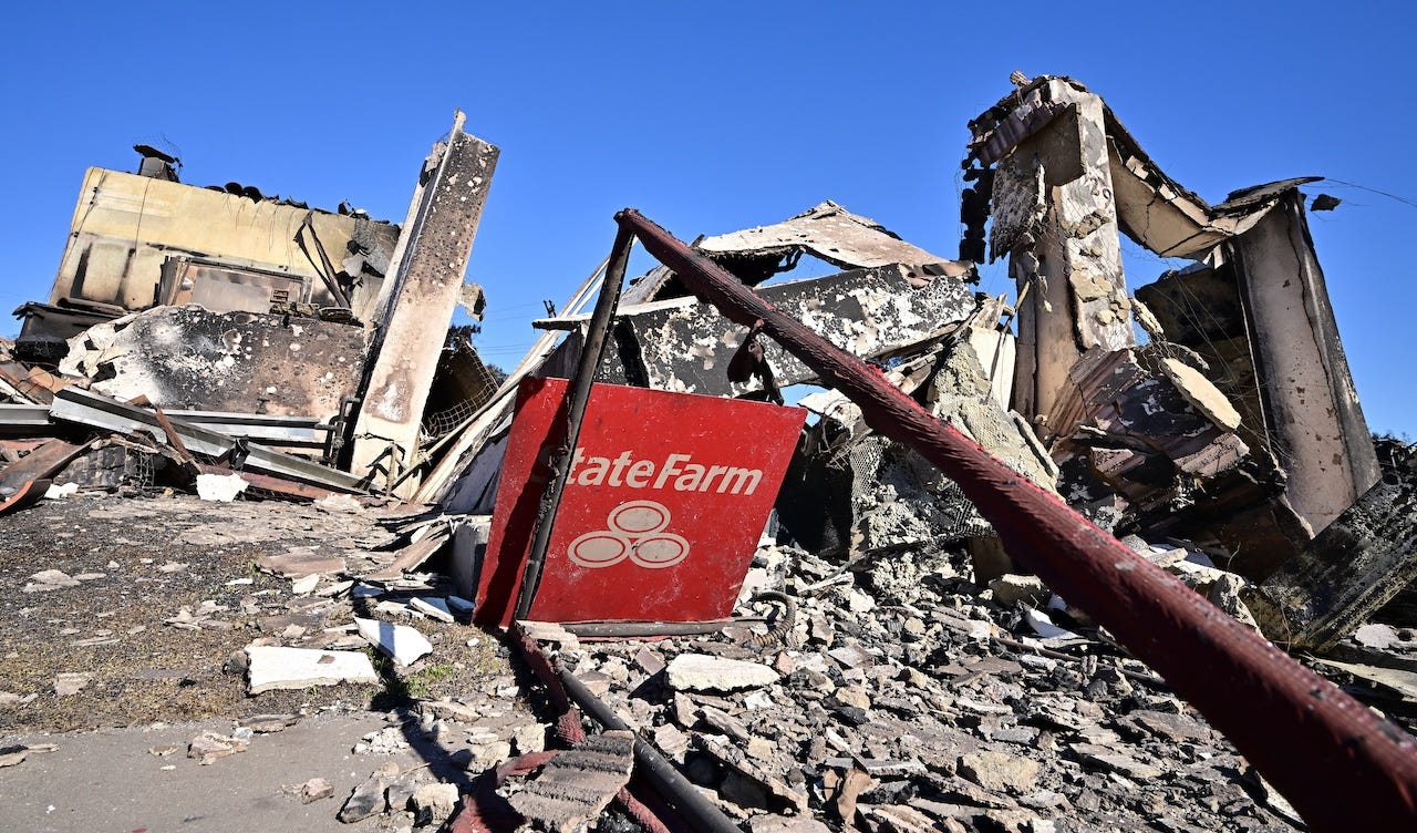 A State Farm insurance company sign sits amid the rubble of a building destroyed by the Palisades Fire on Sunset Boulevard in the Pacific Palisades neighborhood of Los Angeles.