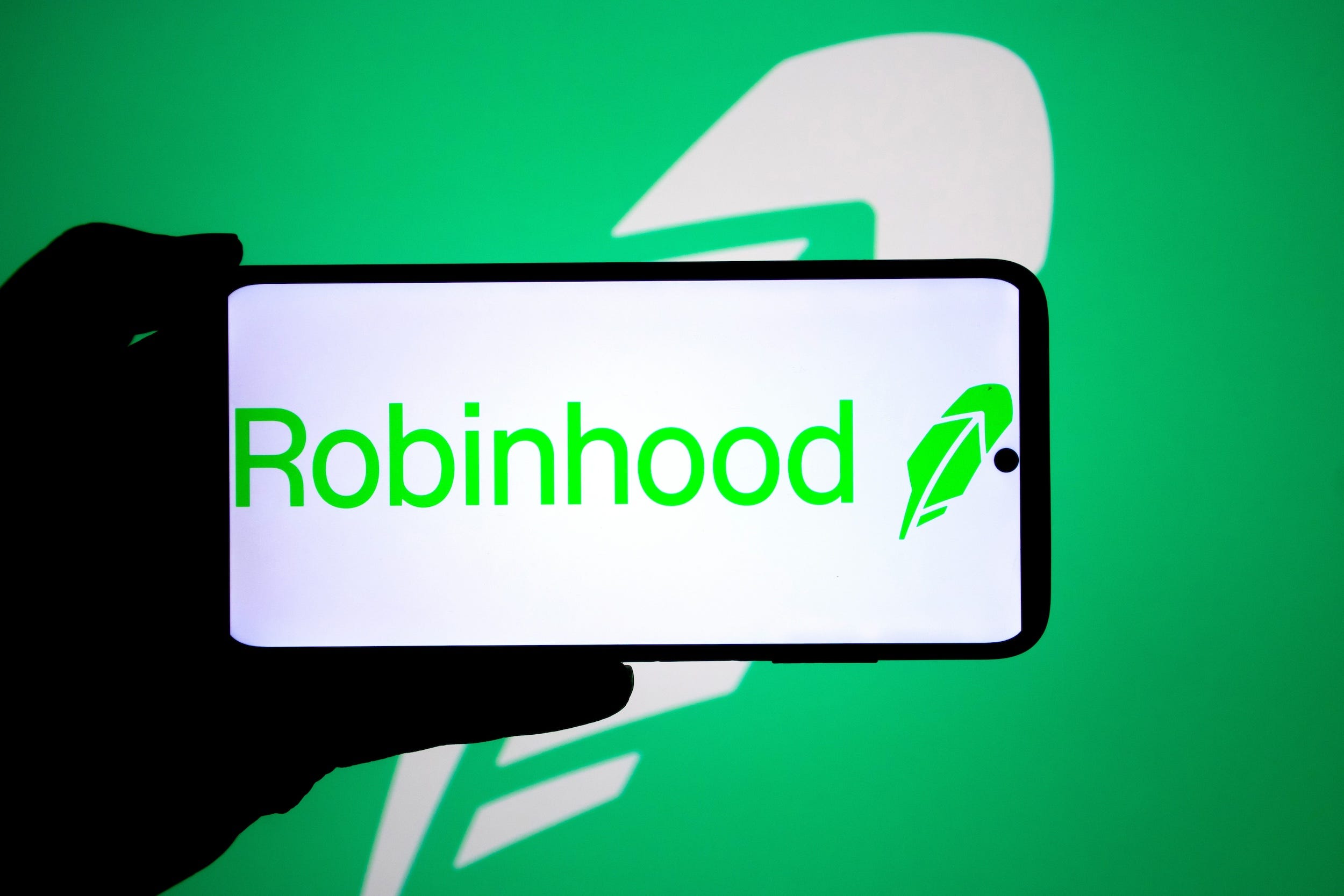 Someone holds a phone displaying Robinhood's logo